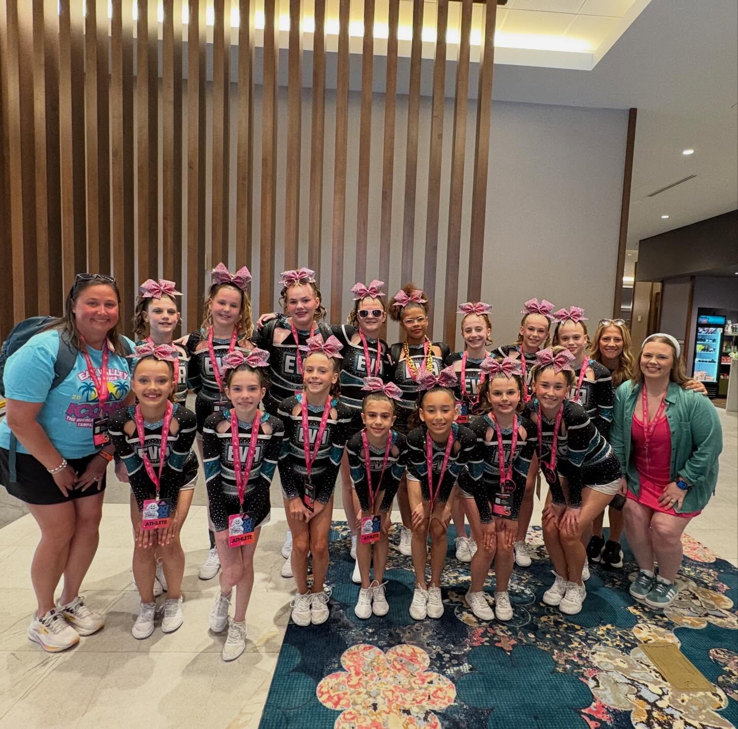 EVA team and coaches posing in hotel lobby with medals